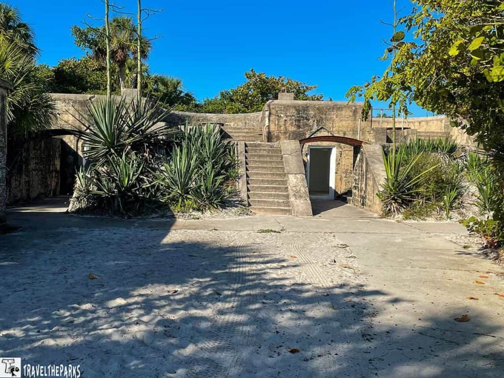 Concrete fort Dade Ruins with stairs and tropical plants under a blue sky.

