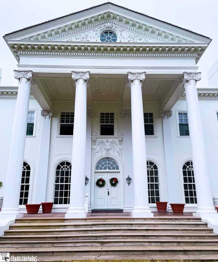 Front view of Plum Orchard Mansion with white columns and a pediment.