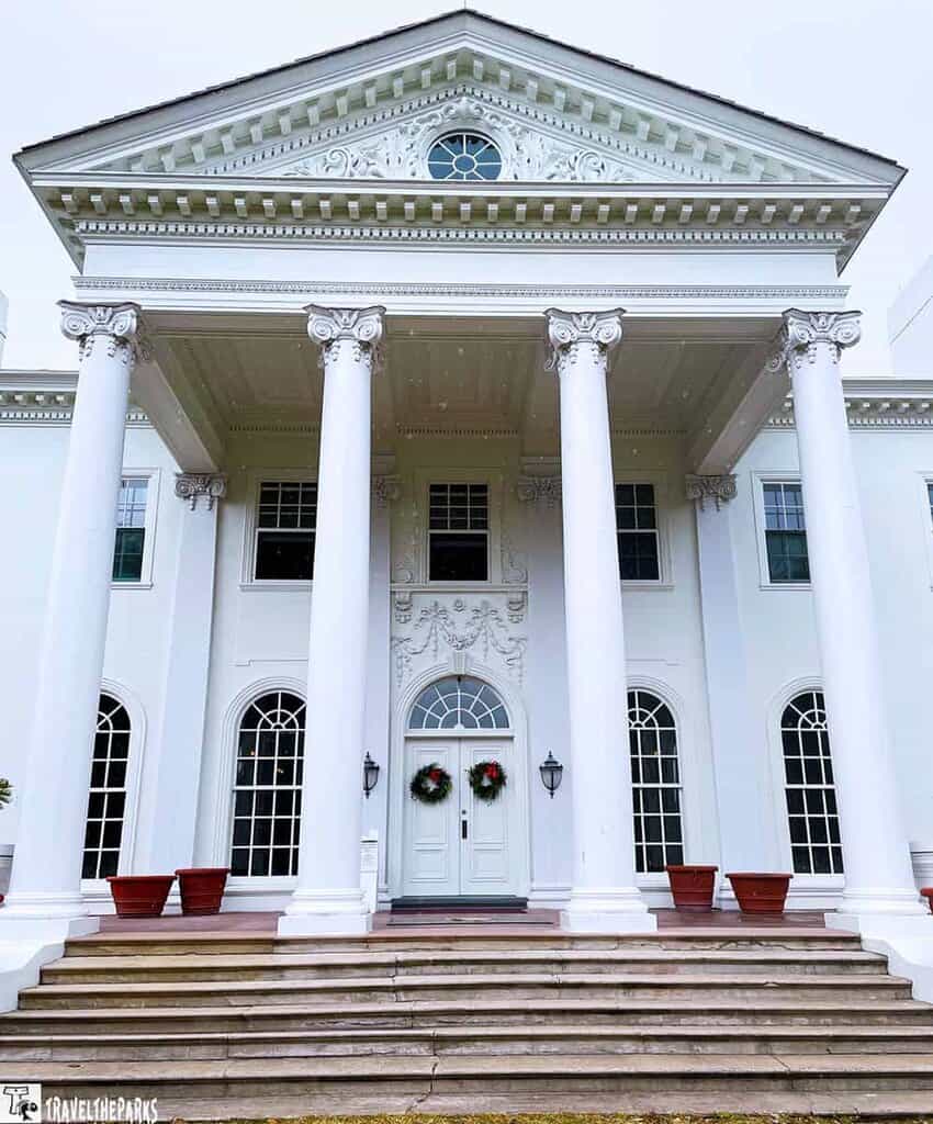 Front view of Plum Orchard Mansion with white columns and a pediment.