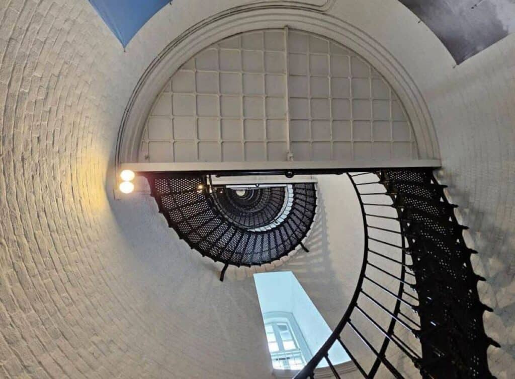 View of a spiral staircase inside a lighthouse, looking upwards.