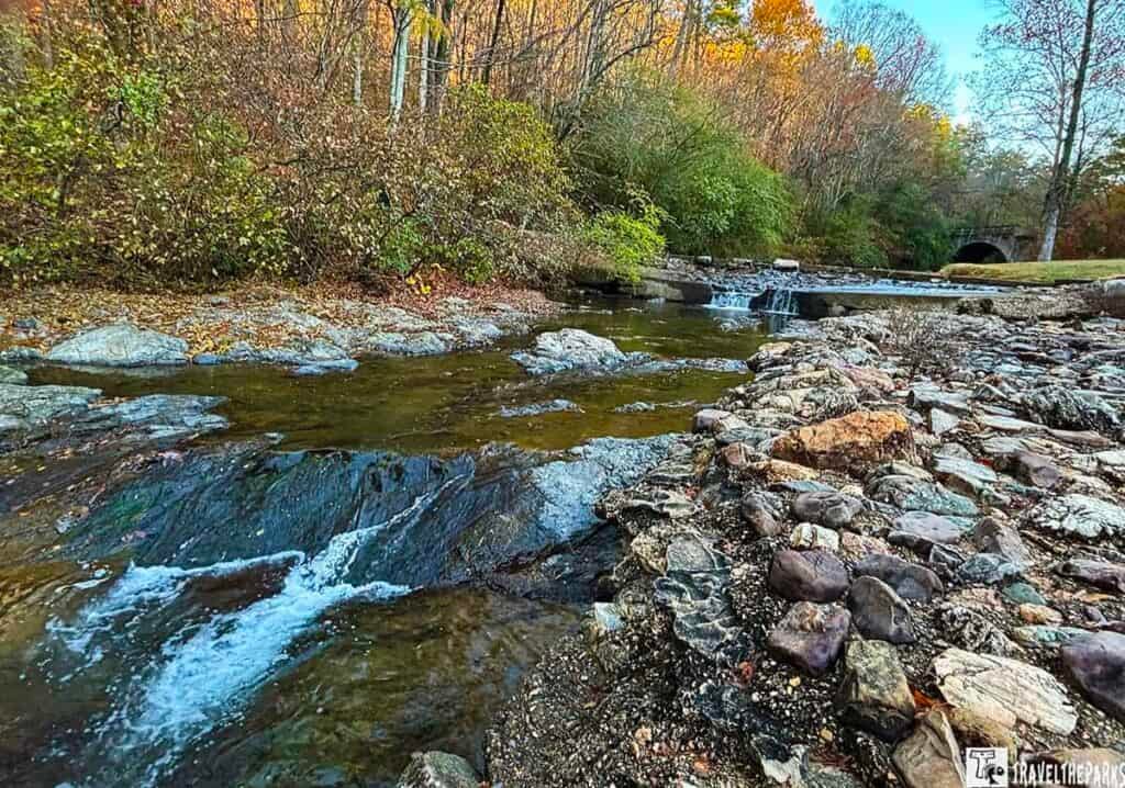 A tranquil stream with small waterfalls and rocky banks, surrounded by autumn foliage at Gulpha Gorge Campground.