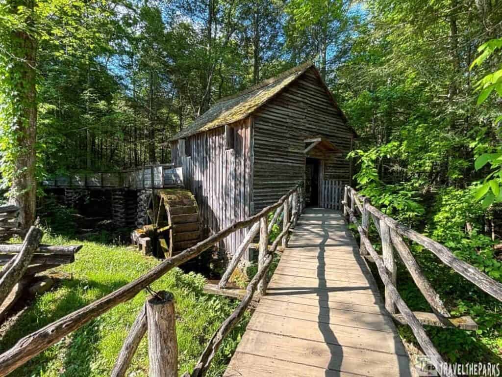 Historic Cable Grist Mill with a wooden waterwheel and bridge in a forested area.

