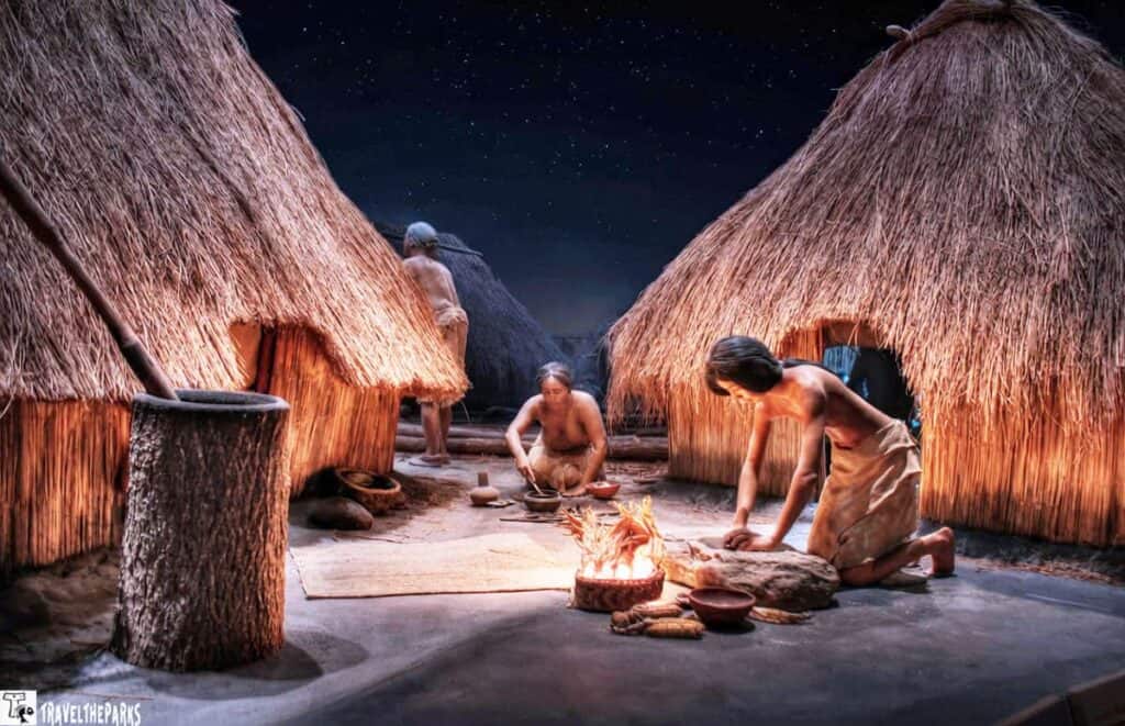 Diorama depicting daily life at Cahokia Mounds State Historic Site with figures outside straw-thatched huts.