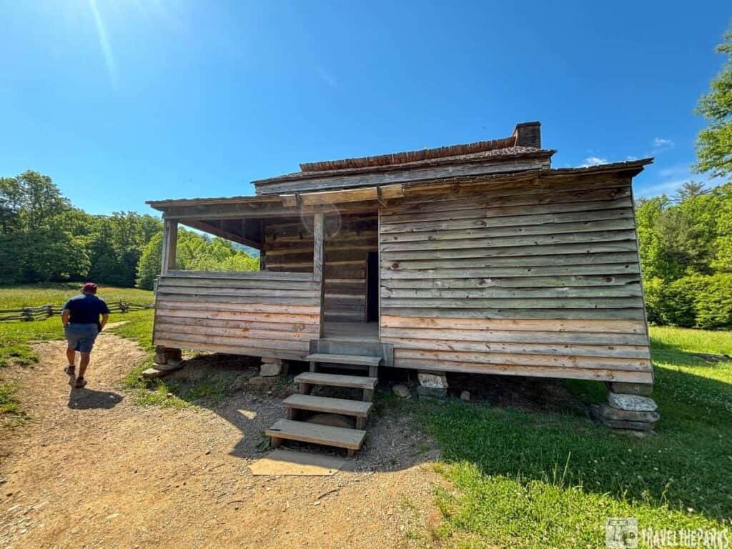 Dan Lawson Place Cades Cover: Rustic wooden cabin with a porch in a green, wooded area.

