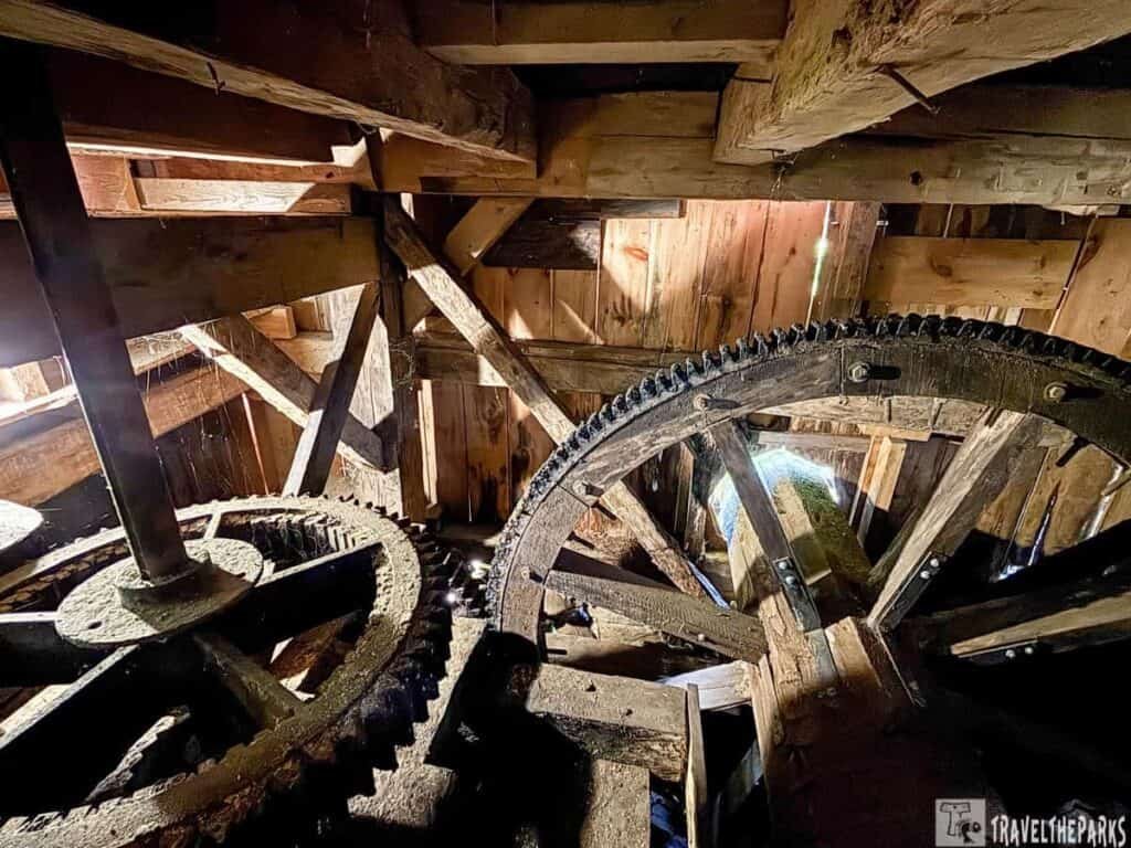 Cades Cove travel guide: Interior view of a wooden gristmill with large gears and beams.