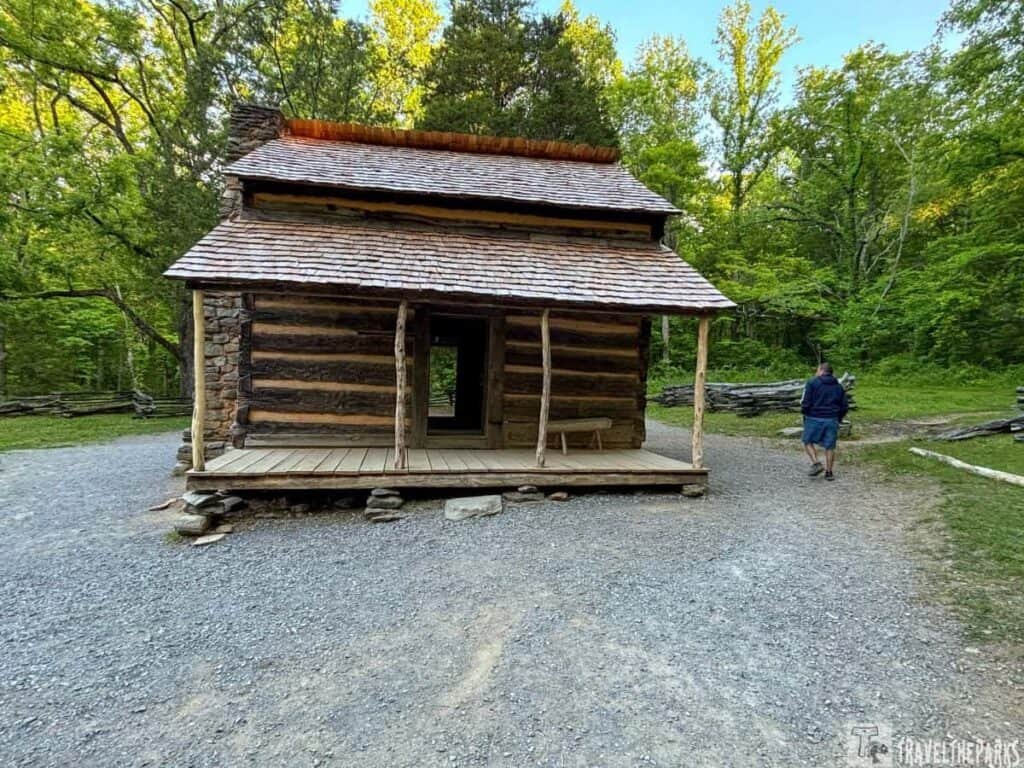 John Oliver Cabin at Cades Cove with surrounding trees and gravel path.

