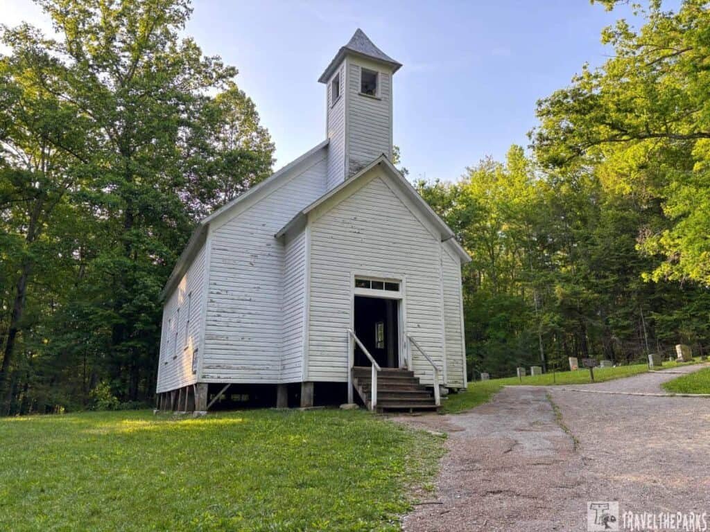 A white wooden church with a bell tower, surrounded by trees, at the Missionary Baptist Church in Cades Cove.

