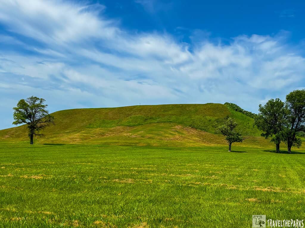 Cahokia Mounds State Historic Site: Monks Mound with grass and trees under a clear blue sky.