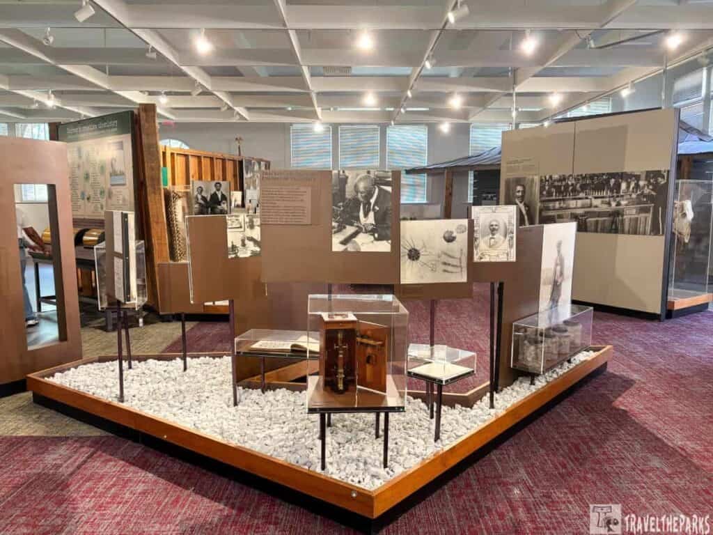 Interior exhibit at the Tuskegee Institute featuring historical displays, artifacts in glass cases, and information panels depicting the institution's legacy.

