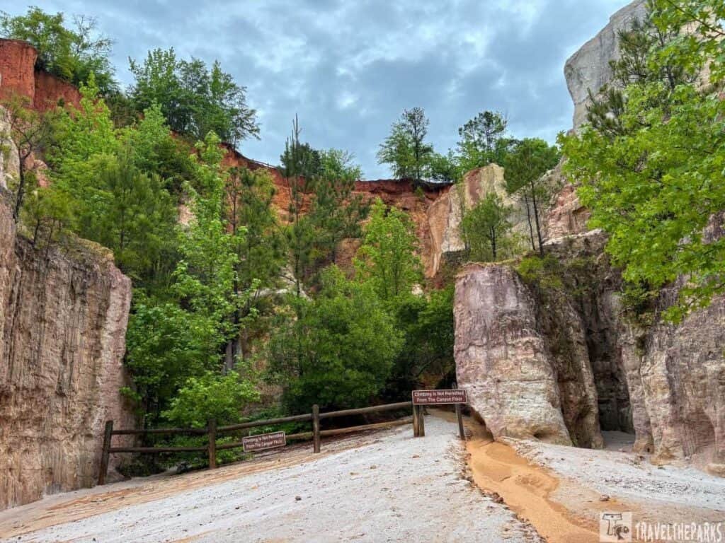 Providence Canyon with colorful cliffs, green trees, and a sand path.