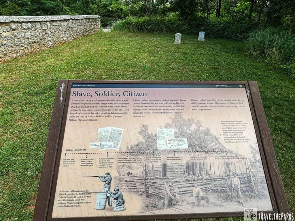 Interpretive sign about William Holland’s life at Stones River National Battlefield, surrounded by a green grassy area and gravestones.

