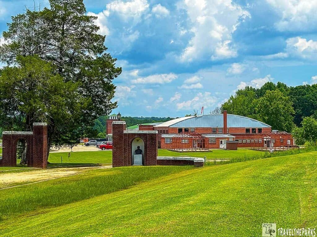 View of the Tuskegee Airmen National Historic Site featuring a brick entrance with a bust and a large red brick building in the background, set in a green landscape under a partly cloudy sky.