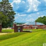 View of the Tuskegee Airmen National Historic Site featuring a brick entrance with a bust and a large red brick building in the background, set in a green landscape under a partly cloudy sky.