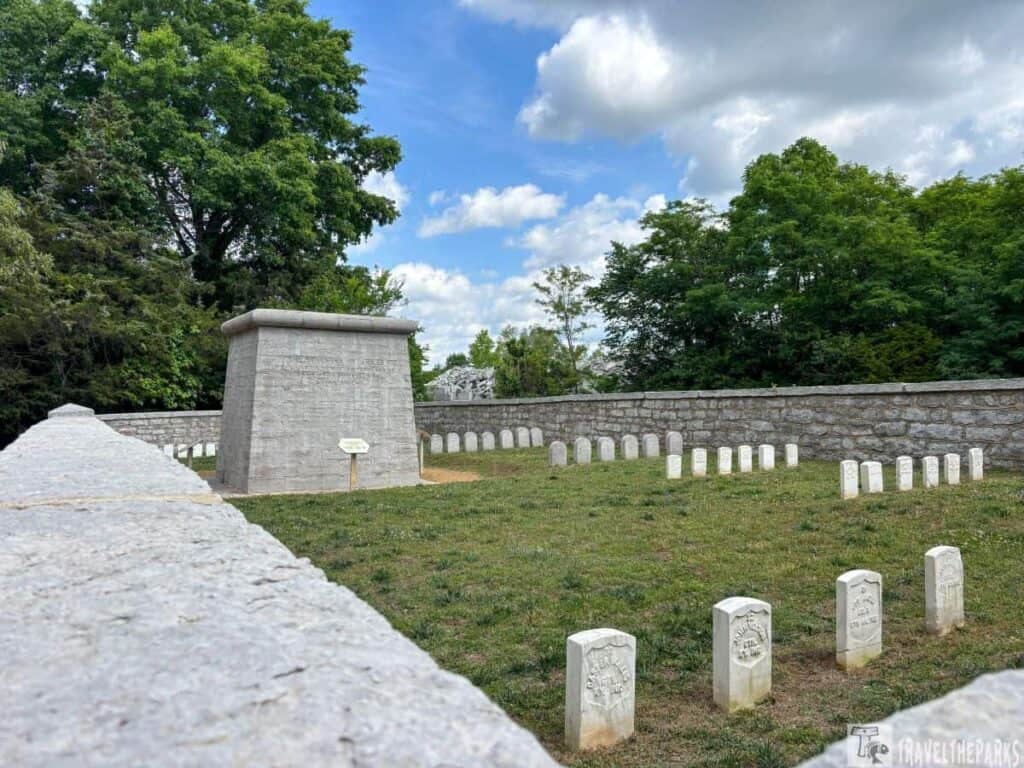 Hazen Brigade Monument at Stone River National Battlefield, with white gravestones and lush greenery in a partly cloudy sky.