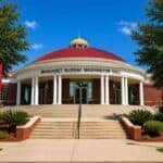 Margaret Murray Washington Hall at Tuskegee Institute, featuring a red domed roof, white columns, and a staircase leading to the main entrance, with green landscaping around.