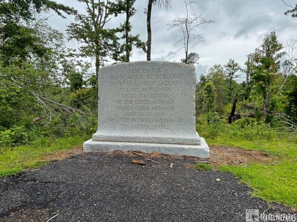 Granite monument at Horseshoe Bend National Military Park with an engraving honoring General Andrew Jackson's victory over the Creek Indians, surrounded by a natural landscape.
Transcribed Text:
HERE ON THE HORSESHOE BATTEGROUND
GENERAL ANDREW JACKSON
AND HIS MEN
BROKE THE POWER
OF THE CREEK INDIANS
UNDER CHIEF MENAWA
MARCH 27, 1814
ERECTED BY THE CONGRESS OF
THE UNITED STATES