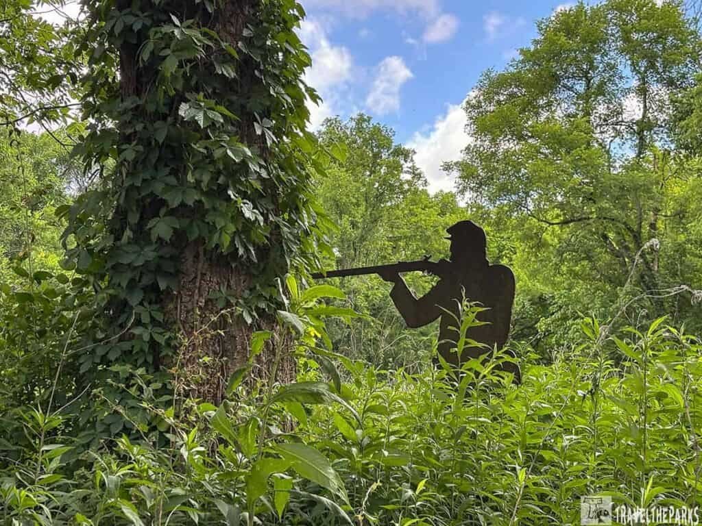 Silhouette of a soldier with a rifle standing among dense green foliage at Stones River National Battlefield.