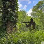 Silhouette of a soldier with a rifle standing among dense green foliage at Stones River National Battlefield.