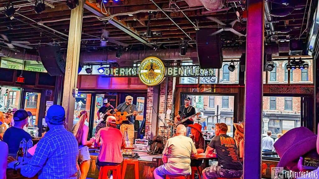 Nashville broadway Street Interior view of Dierks Bentley's with musicians performing on stage. Patrons sit at tables, enjoying the lively atmosphere in a rustic setting.

