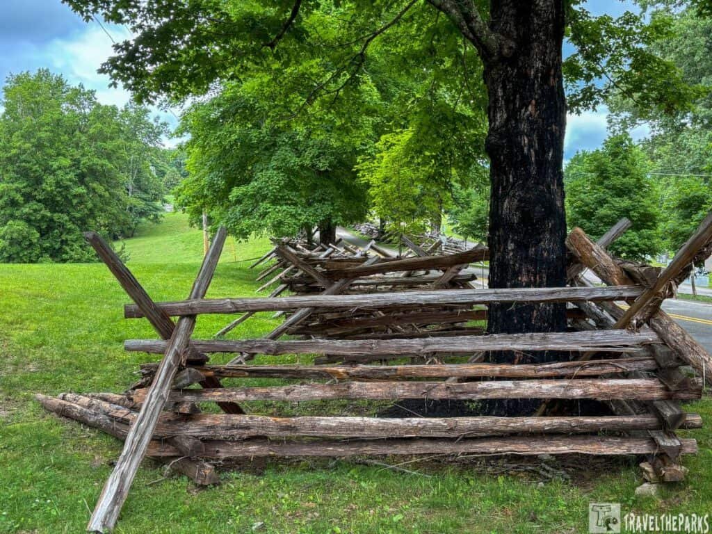 Wooden split-rail fence at Fort Donelson National Battlefield, surrounded by grass and trees under a cloudy sky.