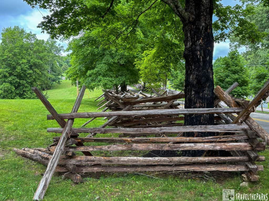 Wooden split-rail fence at Fort Donelson National Battlefield, surrounded by grass and trees under a cloudy sky.