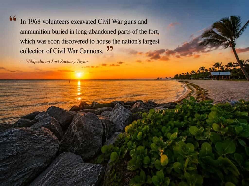 Sunset at Fort Zachary Taylor Historic State Park, featuring rocks in the foreground, water reflecting warm hues, palm trees, and a gazebo, with an overlay of text about the park's history. Transcribed Text: "In 1968 volunteers excavated Civil War guns and ammunition buried in long-abandoned parts of the fort, which was soon discovered to house the nation’s largest collection of Civil War Cannons." — Wikipedia on Fort Zachary Taylor