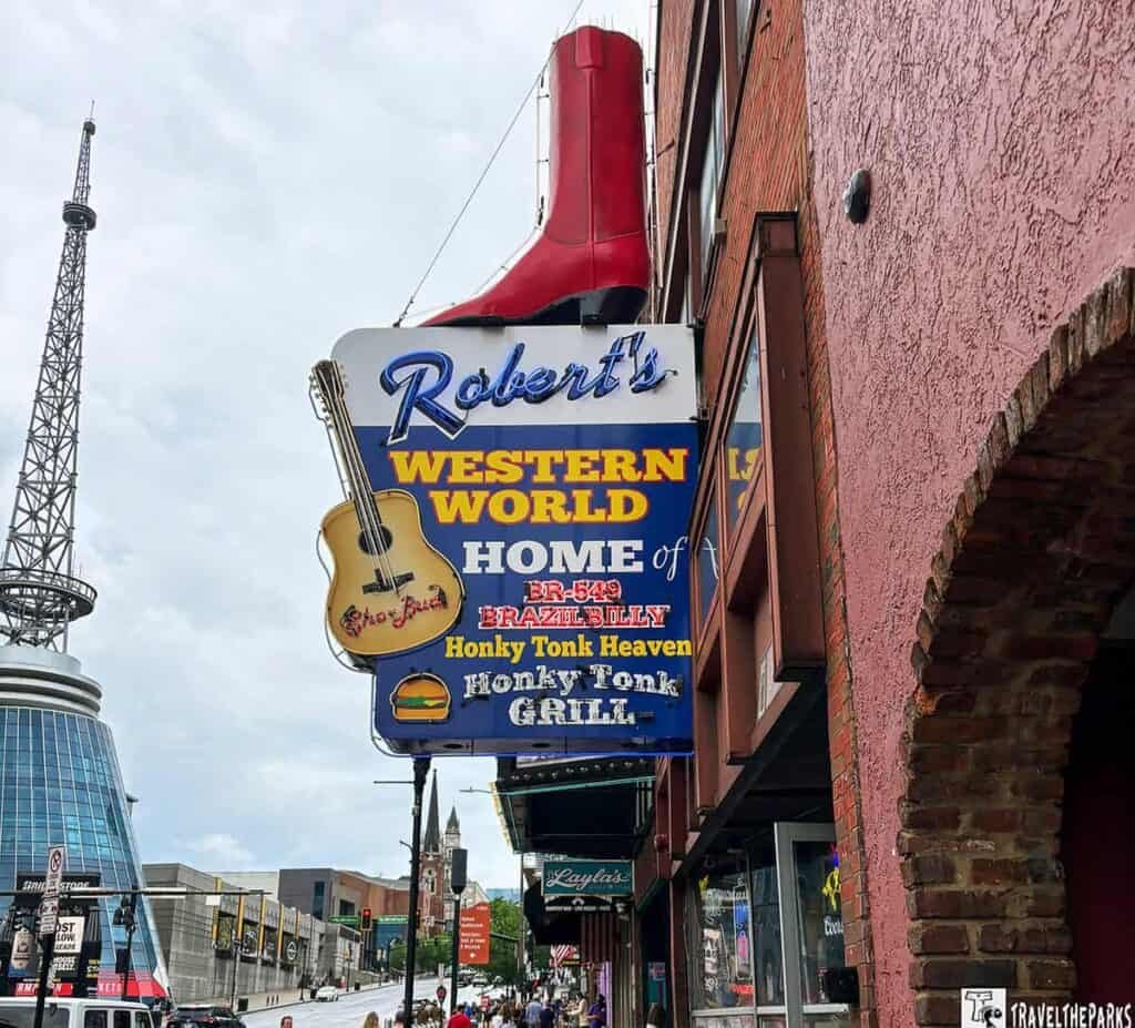A colorful sign for "Robert's Western World" featuring a red cowboy boot, with text indicating live music and dining options.

