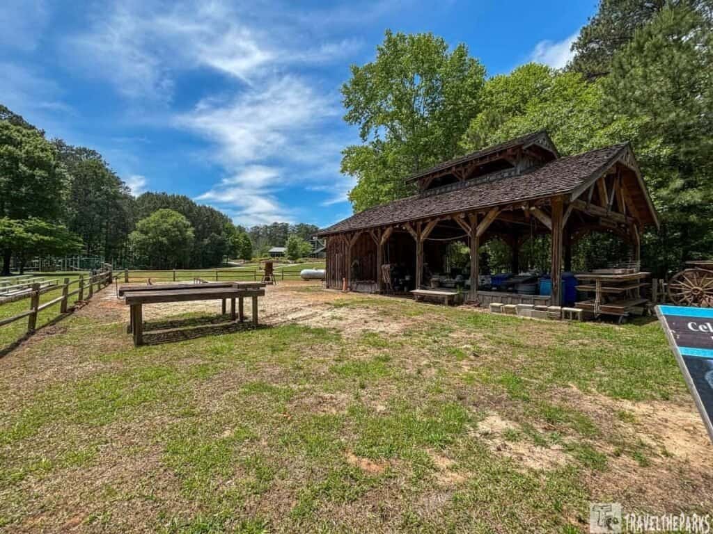 A wooden pavilion at Red Top Mountain State Park surrounded by grass, wooden tables, and trees under a clear blue sky.

