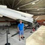 Interior view of the HM-69 Nike Missile Site, featuring a white Nike missile on a launch platform with a person standing beside it, surrounded by stanchions and industrial elements.