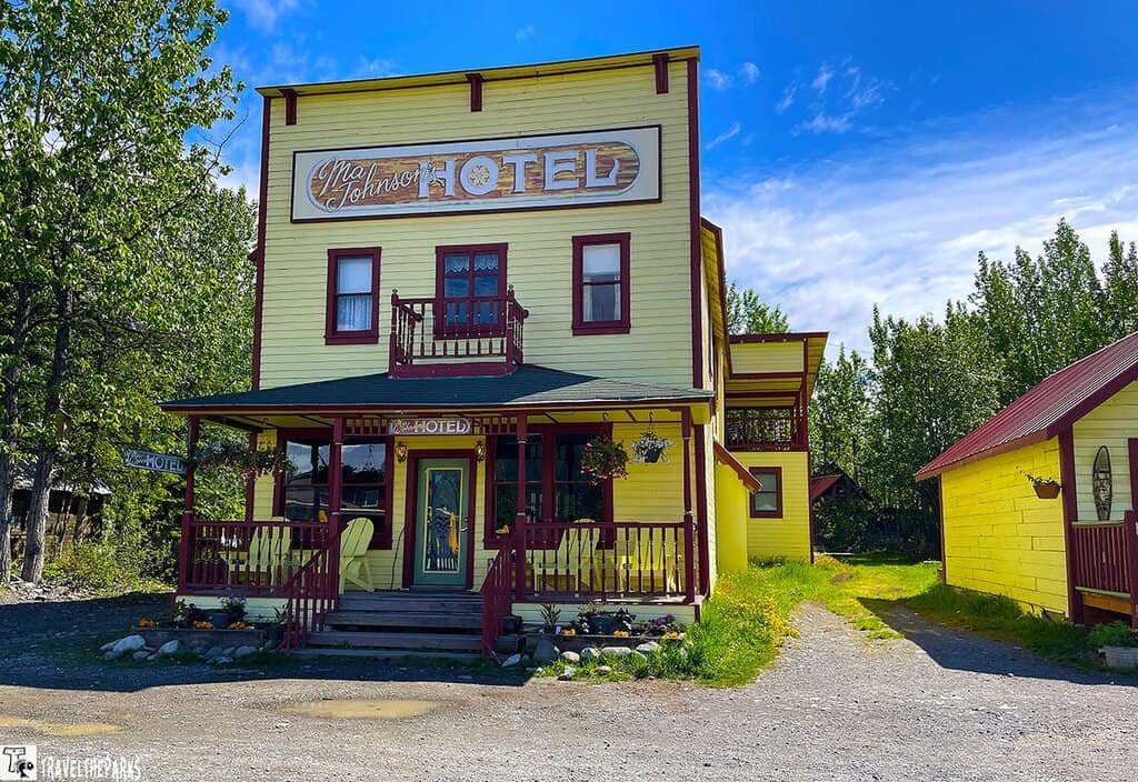 Ma Johnsons Hotel McCarthy Alaska: Historical yellow hotel with red trim and a porch, surrounded by trees.